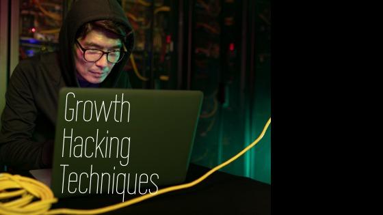 A male hacker in a hood and glasses is working on a laptop with text written on it: Growth Hacking Techniques - Guide to boosting your business with growth hacking - Image